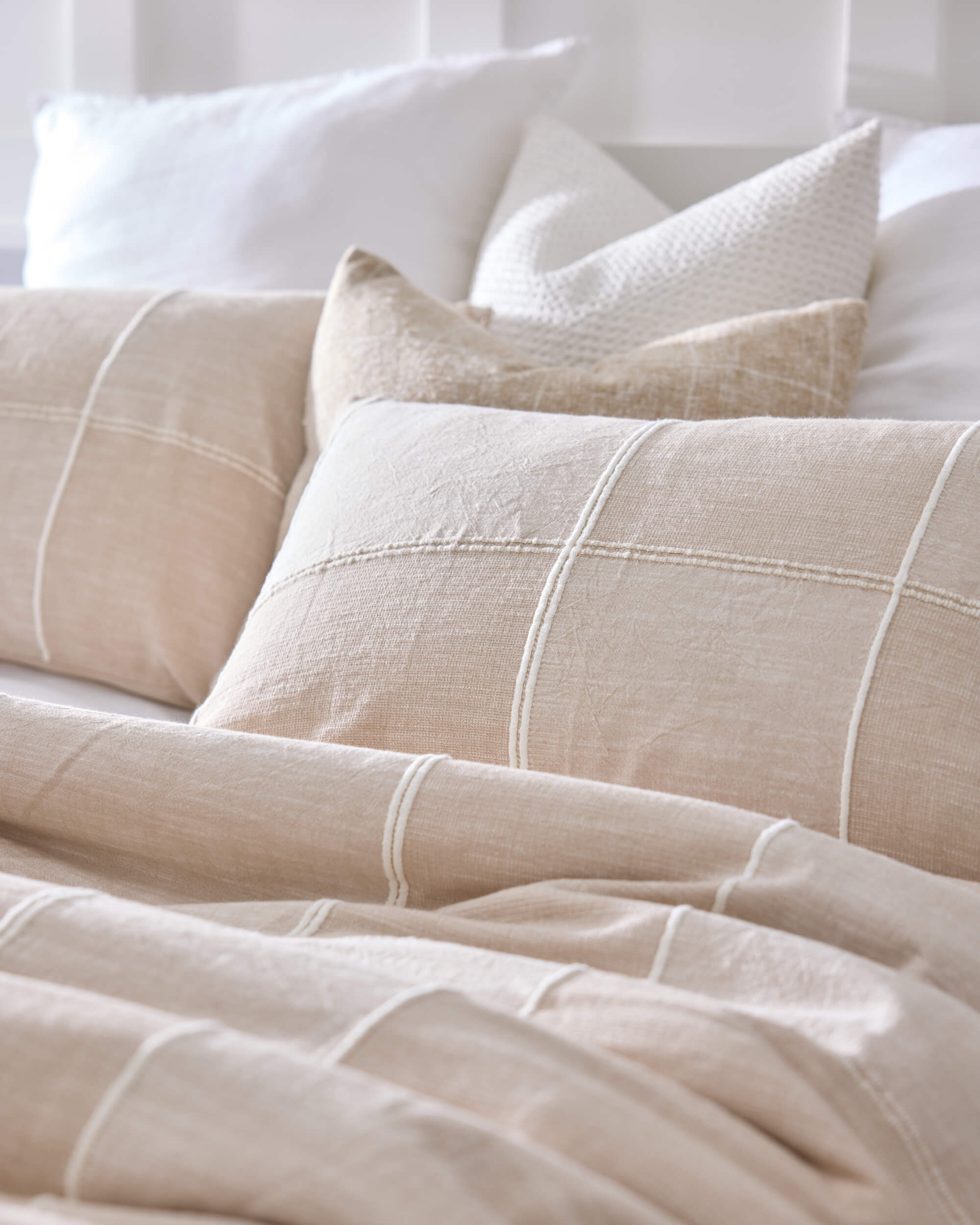 Royal Doulton Whitby beige grid duvet cover styled with matching cushions and white pillows