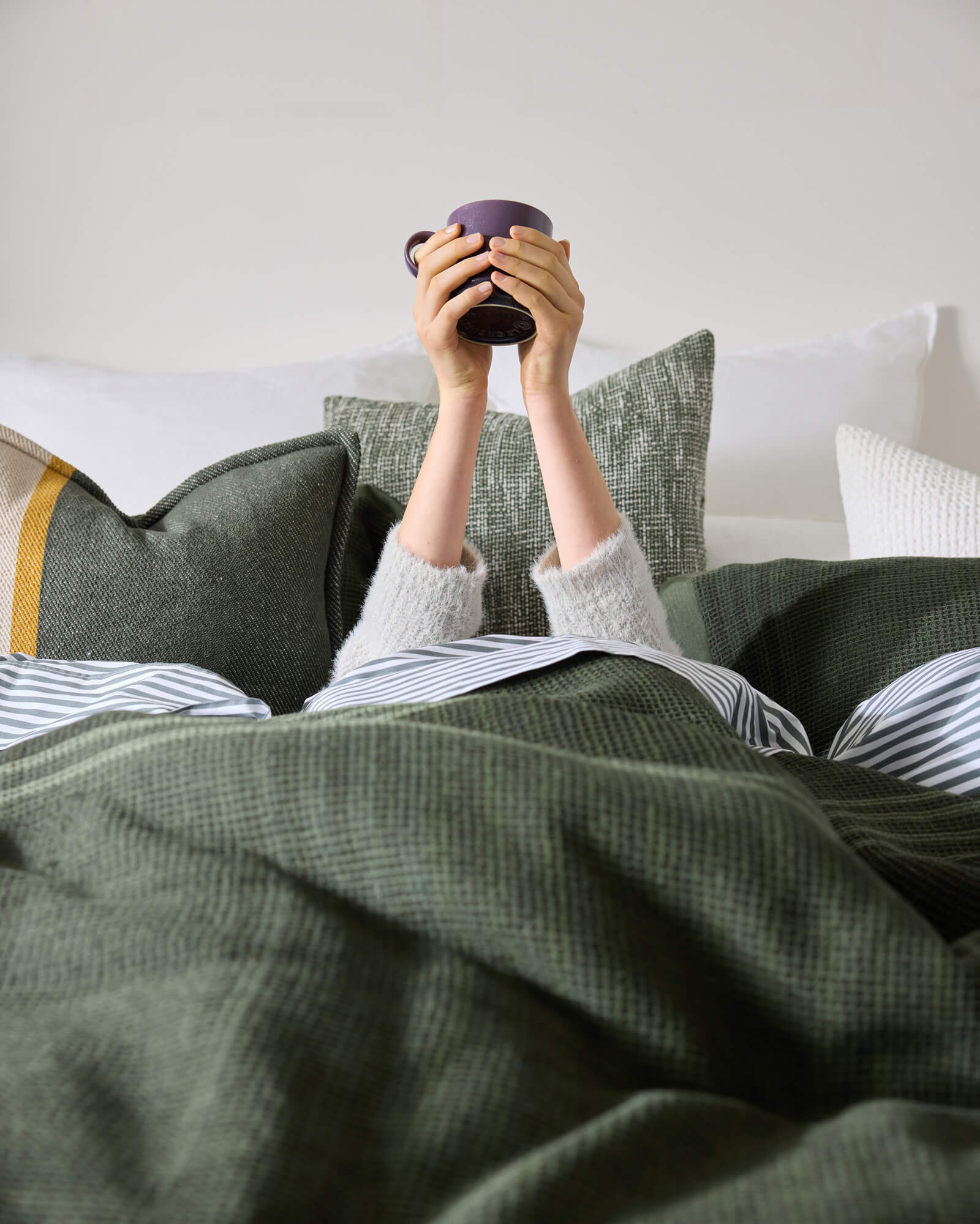 Person lying on a bed with Royal Doulton Hampshire duvet cover styled on a bed with coordinating cushions