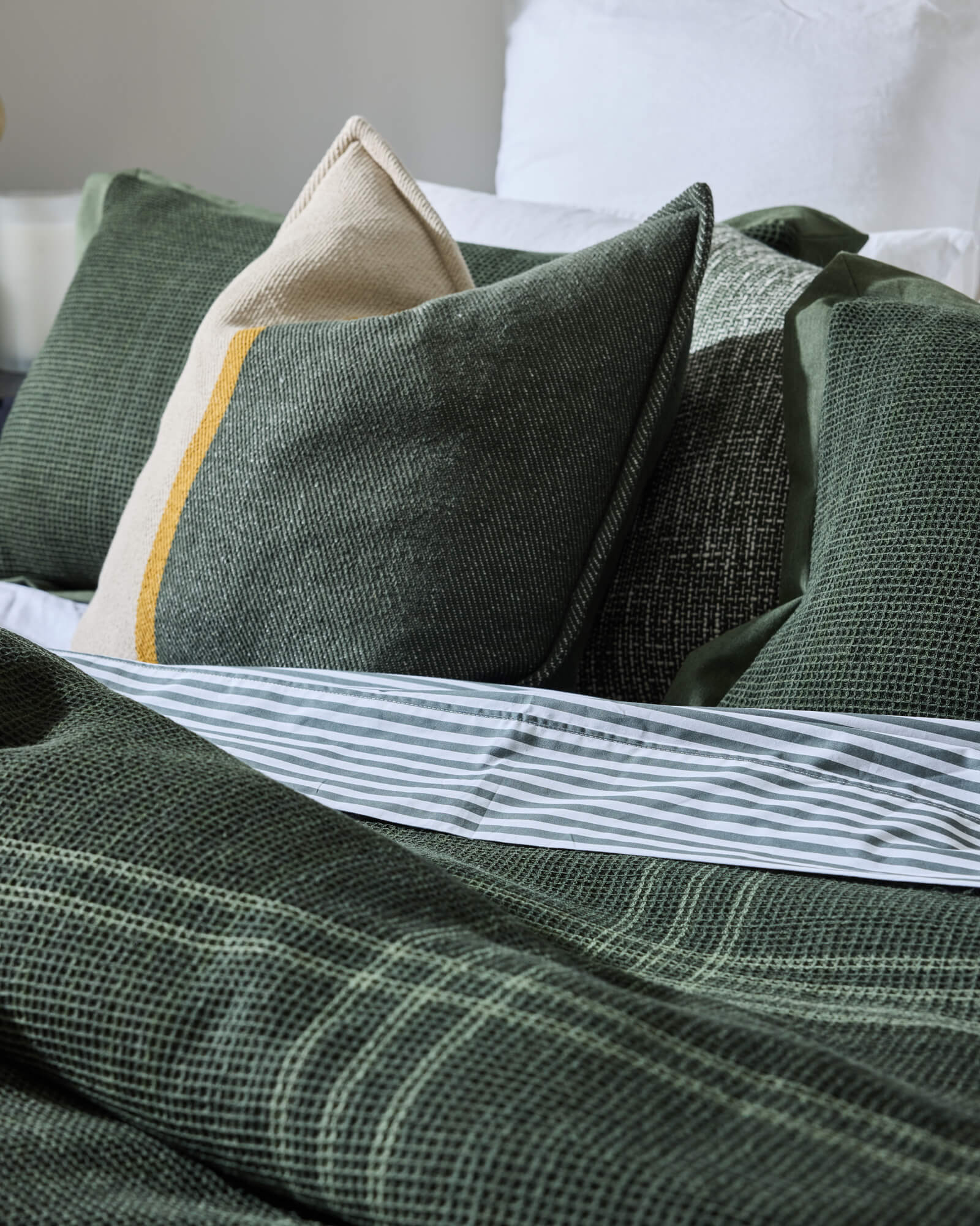 Royal Doulton Hampshire duvet cover styled on a bed with coordinating Levi Printed Sheet​, Ellington Cushion​, Marlowe Olive cushion​.
